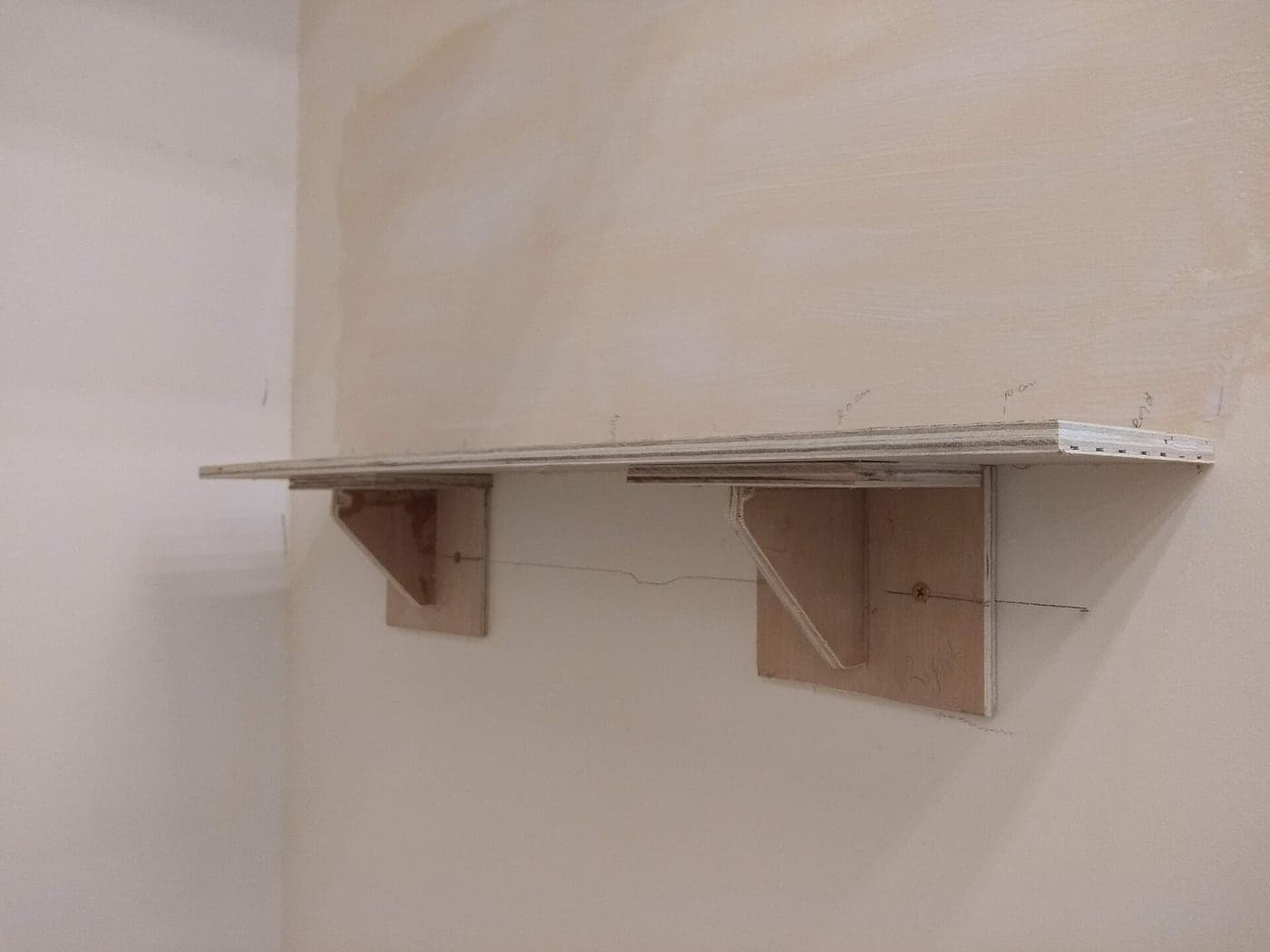 A wall-mounted wooden shelf seen from an angle, showing its brackets