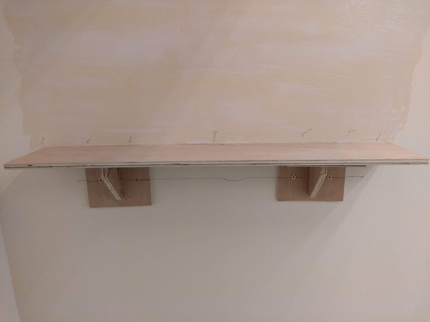A wooden shelf mounted on a wall with wooden brackets